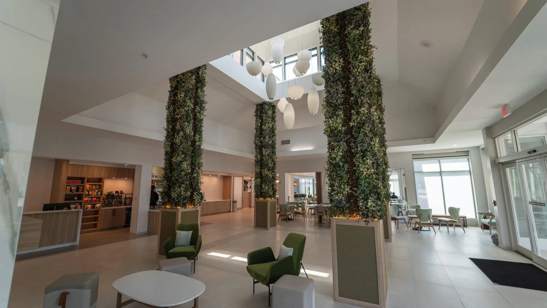 Hilton Garden Inn lobby with tall greenery-covered columns, paneled bases and seating beside reception